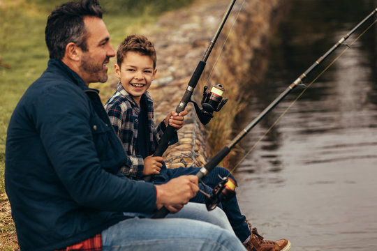 Happy man and kid fishing in a lake