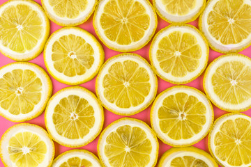 Pattern made from fresh lemon slices on a pink background, overhead view, flatlay. Fruit background.