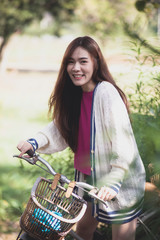 Fototapeta na wymiar cheerful asian younger woman riding on retro bicycle in green park