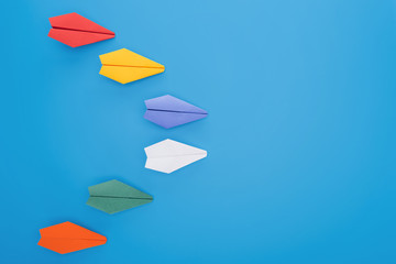 Flat lay with colorful paper planes on blue surface