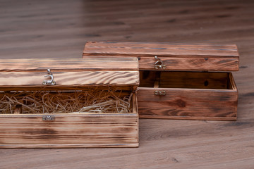 Two wooden luxury gift boxes or caskets on wood background. Vintage open box filled with natural raffia or twine