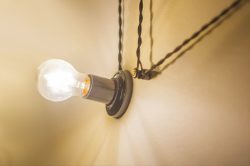 old-style light bulb shines brightly and black wires