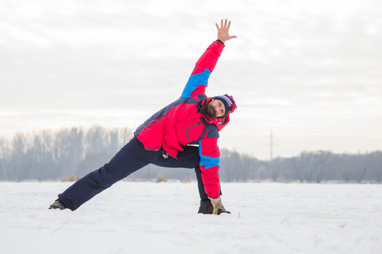 A middle-aged man is engaged in yoga on a frozen river. The Pose Of Trikonasana Uchiha.