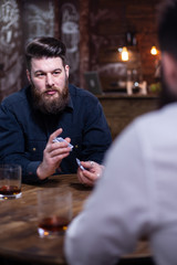 Handsome bearded man looking at his friend and shuffle cards