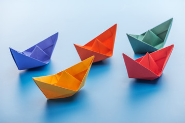 Colorful bright paper boats on light blue surface
