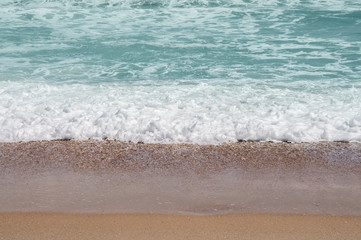 Fototapeta na wymiar Waves breaking on the beach sand