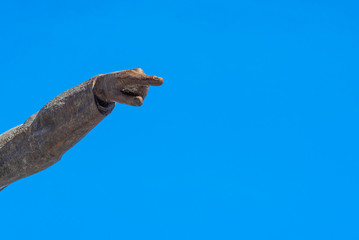 Stone hand with pointing finger and blue sky in the background