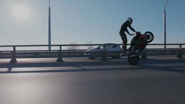 Professional motorcyclists riding on the rear wheel on hight speed. Professional driver perform dangerous tricks on the road in city traffic