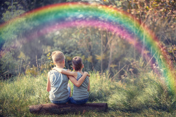 Two little boys friends holding and enjoying nature with rainbow in sunny summer day,