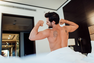 selective focus of tattooed man stretching in bed after wake up