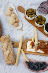 Fototapeta premium Food lay out on picnic blanket. fresh baked bread, olives and photocam lay on white blanket. Picnic prepare decoration