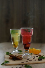 two glasses with colored hot drinks from which steam comes. winter hot seasonal drinks