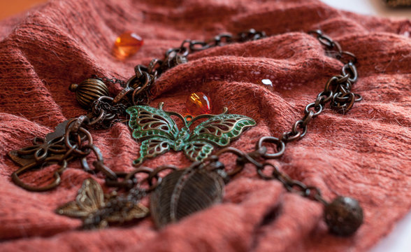 selective focus of chain with decorative leaves, beads, butterflies on red cloch