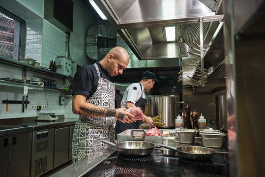 Just high quality. Concentrated chef with tattoos on his arms holding fresh red meat ant thinking about future dish