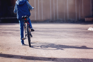 Children on a bicycle at asphalt road in early morning summer day.