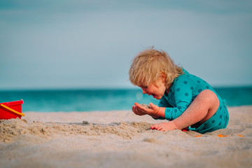cute little girl eating sand on beach
