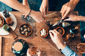 high angle view of hands picking up food from a table: togetherness, friendship, appetizer, aperitif, tapas moment concept - obrazy, fototapety, plakaty