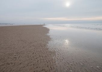 Watery sunlight in the winter on the Fylde shore at Lytham St. Anne's on the Lancashire coast, England UK. Lovely muted colours and reflections.