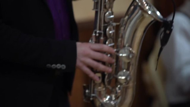 A man in a black jacket and a purple shirt playing the saxophone, the average plan