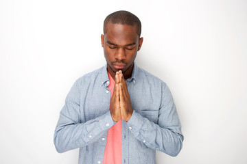 Fototapeta na wymiar peaceful young black man praying with hands clasp together by white wall