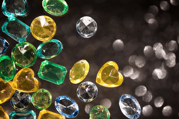 Shiny yellow, green and blue glass, jewelry, placers on a black background with blurred spots.