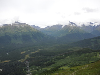 Naklejka premium View from atop a mountain in the wilderness of Alaska. Peaks and ocean stretching off into the sky and clouds