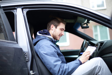 man signs a document while sitting in the car