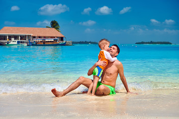 Naklejka premium Toddler boy on beach kissing father