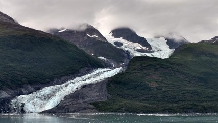 Glaciers within Glacier Bay National Park in Alaska. Glaciers coming over mountain peaks and sliding into the Pacific Ocean