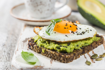 Sandwich with avocado, egg and spinach on white wooden background. Healthy diet breakfast