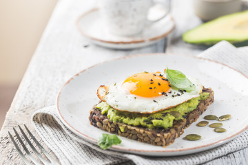 Sandwich with avocado, egg and spinach on white wooden background. Healthy diet breakfast