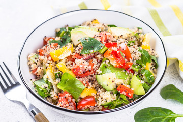 Quinoa salad with fresh vegetables on white.