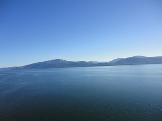 Obraz premium Calm Pacific Ocean in the inside passage in Alaska blue sky meets mountains and blue sea in a peacefully clear view