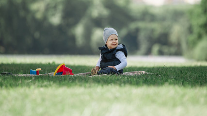 little boy sitting on the lawn on a spring day
