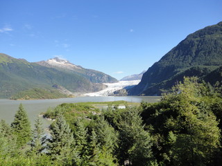 Fototapeta na wymiar Mendenhall Glacier Juneau Alaska. Mendenhall Glacier flowing into Mendenhall Lake in between mountains with Nugget falls. Perfect tourist location