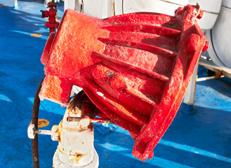 Close-up of a rusty red color painted flood light against a blue floor on deck of a ship in Asia