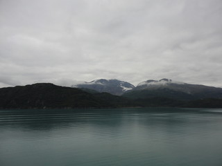 Mountain Filled horizon on the pacific ocean. Inside passage Alaska with glaciers at the peaks under a cloudy sky