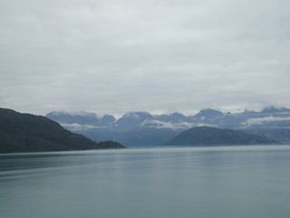 Mountain Filled horizon on the pacific ocean. Inside passage Alaska with glaciers at the peaks under a cloudy sky