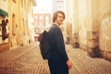 A man travels in Europe. A man smiles, walks through the streets of the old city, with a briefcase. Student travels alone