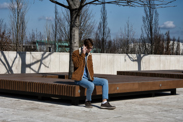 Young student is resting in the park and the phone.