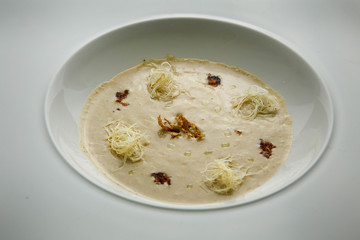 closeup seafood cream soup decorated with dried squid and soy sauce