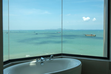 View from a bath room in a luxury hotel, seeing bathtub with a faucet set and a beautiful sea view of Pattaya and islands around. 