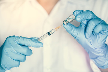 Doctor, nurse, scientist, man or women holding flu, hpv, rabies, mumps, measles, polio, or diphtheria vaccine bottle with syringe with needle prepare for immunization in baby, child or adult patient