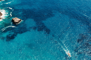 Yacht at the sea in Italy. Aerial view of luxury floating boat on transparent turquoise water at sunny day. Summer seascape from air. Top view from drone. Seascape with motorboat in bay.