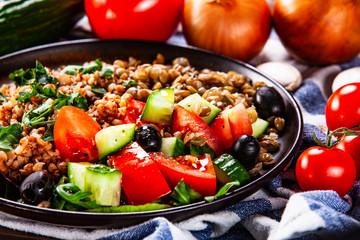 Groats with lentils and vegetables on wooden table