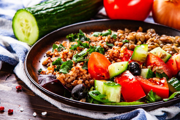 Groats with lentils and vegetables on wooden table