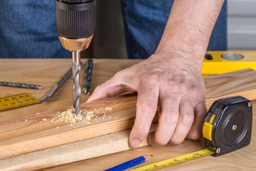 Carpenter drilling wood using portable drilling machine