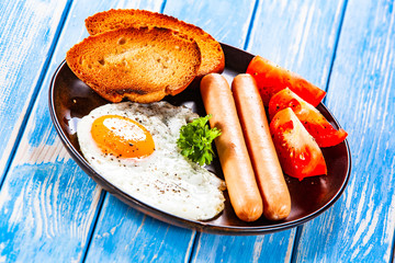 English breakfast - fried egg, sausages, toasts and vegetables