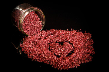 heart painted in red organic sea salt poured out from small glass jar