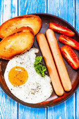 English breakfast - fried egg, sausages, toasts and vegetables